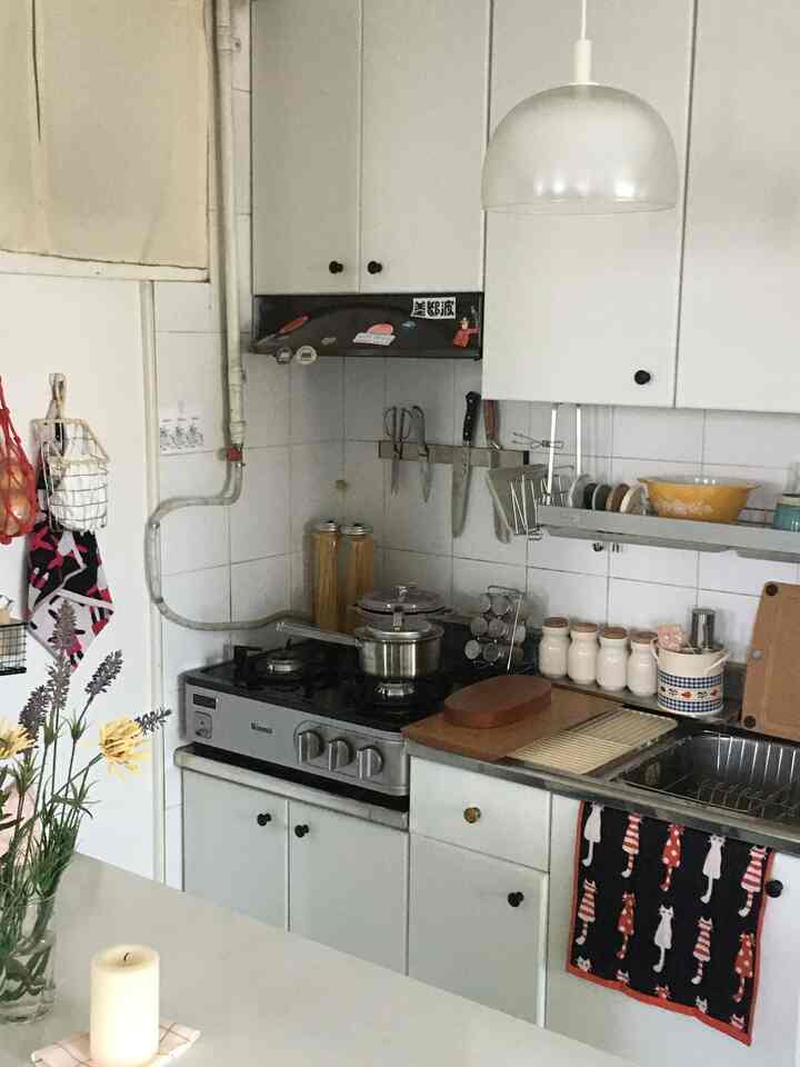 白を基調としたコンパクトなキッチン、整頓された包丁掛けと調味料入れが配置された自然で落ち着いた雰囲気のインテリア