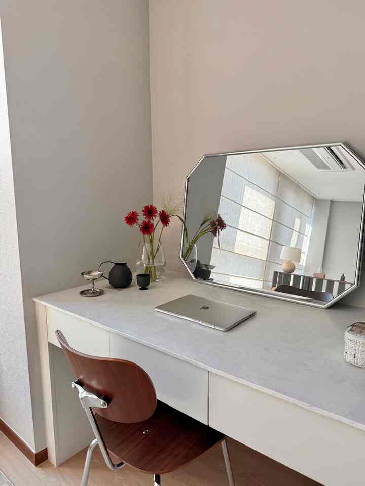 ベージュ色の壁と化粧台を中心としたモダンな書斎空間、木製の椅子と大きな八角形の鏡が調和したインテリア