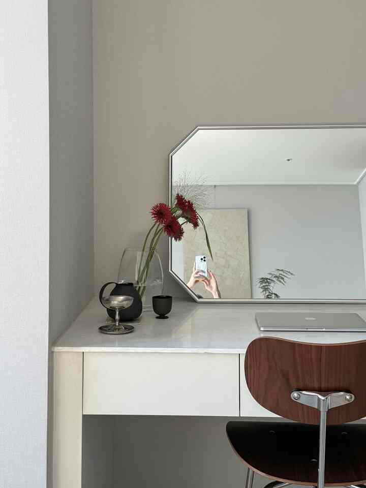 ホワイトとシルバー調のすっきりとした化粧台空間、大きな鏡と木目調の椅子が配置されたシンプルモダンなインテリア