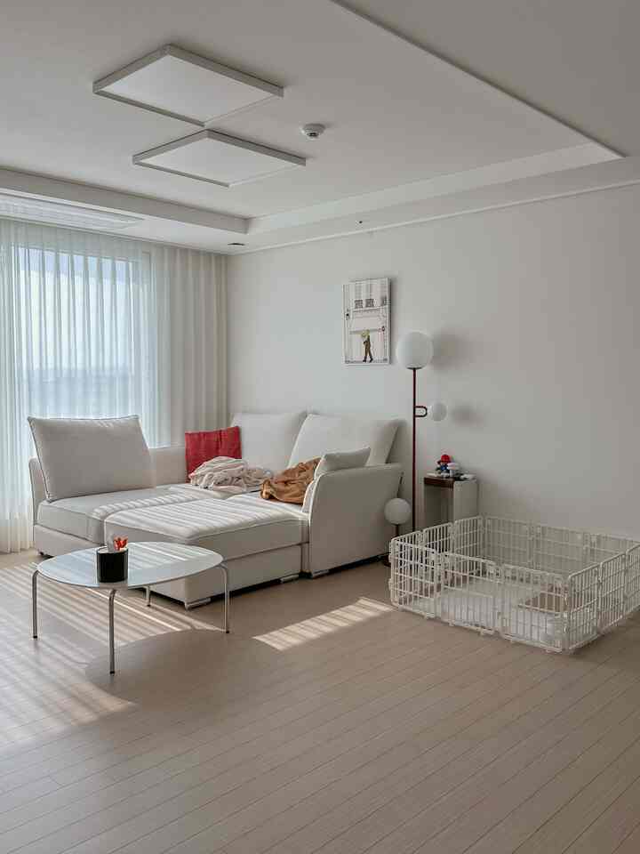 白を基調としたリビングルーム、モジュラーソファと犬用セーフティフェンスが配置された落ち着いた雰囲気の空間