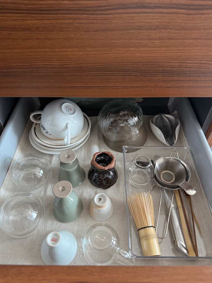 温かみのある木目調のキッチンアイランドの引き出し内部、整理されたティーカップと茶道具が配置された雰囲気のある空間