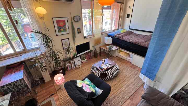 暖かいベージュとブラウンの色調のリビング、ソファやコーヒーテーブル、ベッド、植物が配置された雰囲気のあるインテリア