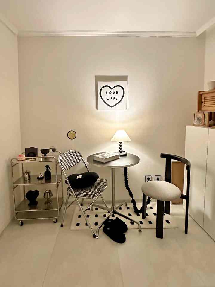 白い壁と床、シンプルな丸テーブルと2つの椅子が配置された、落ち着いたミニマルな小さなダイニングスペース