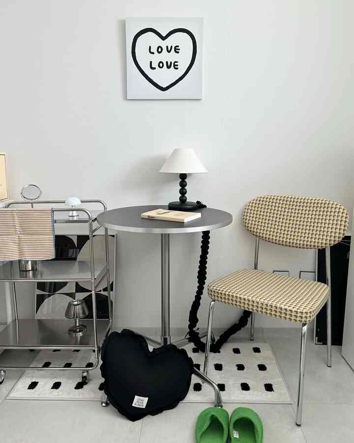 白とグレーのトーンの小さなカフェ風空間、サイドテーブルとチェック柄チェアが配置された雰囲気のあるインテリア