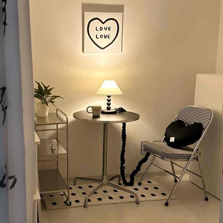 白と黒のモダンなダイニングルーム、丸テーブルとチェア、ムードランプ、かわいい絵が配置された雰囲気のあるインテリア