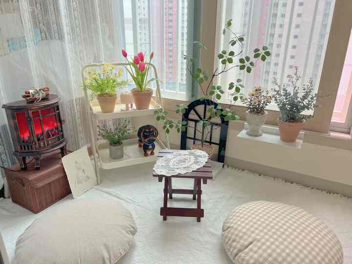 柔らかなベージュとナチュラルカラーのバルコニー空間、木製スツールやクッション、植物が配置された雰囲気のあるインテリア