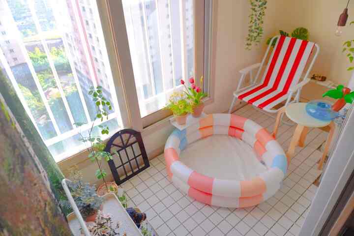 明るいベージュ調のバルコニー、ミニプールとストライプ柄のアウトドアチェアが置かれた自然で温かみのあるインテリア