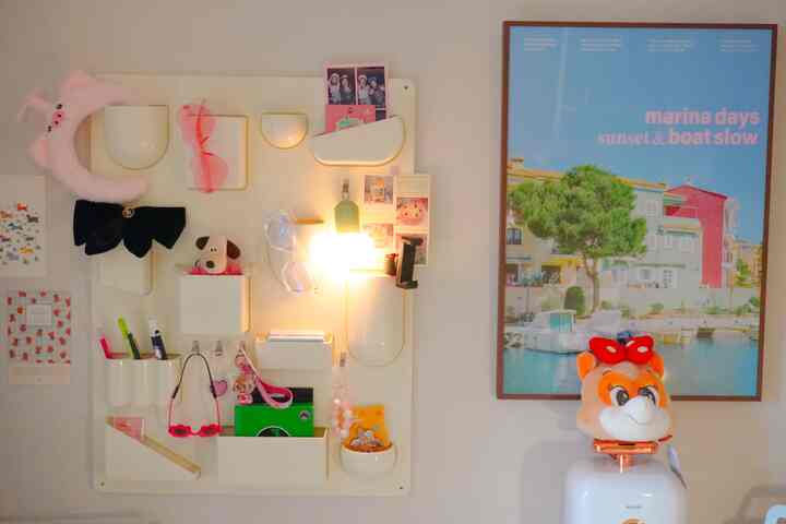 白とピンクの色調の子供部屋の壁に多様な収納アイデアとかわいい少女インテリアが配置された暖かみのある空間