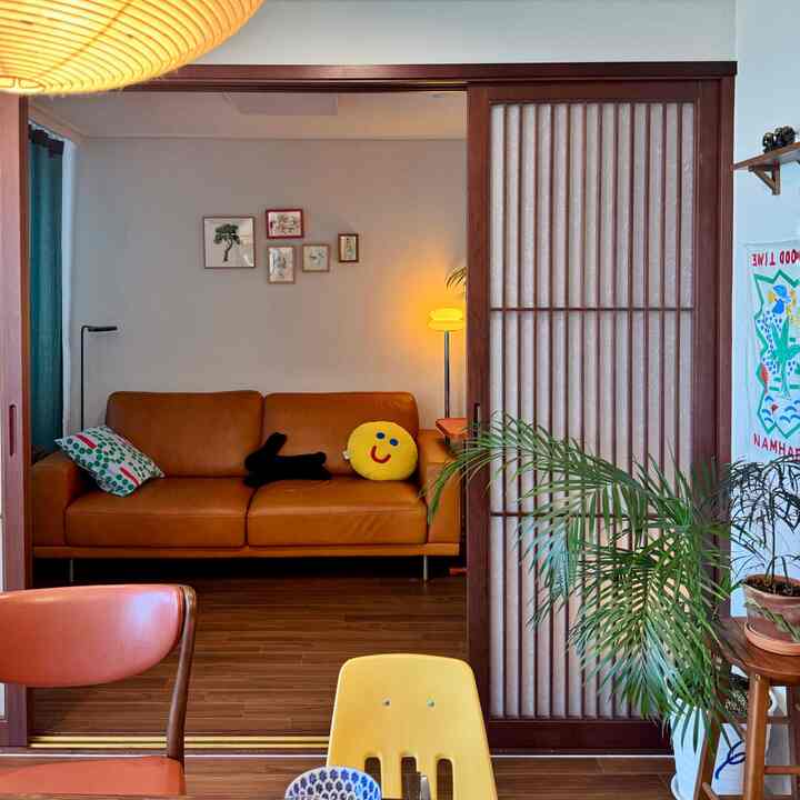 温かみのあるオレンジ色のソファと和紙アクリルの引き戸が配された小さなリビング、落ち着いた読書とくつろぎの雰囲気