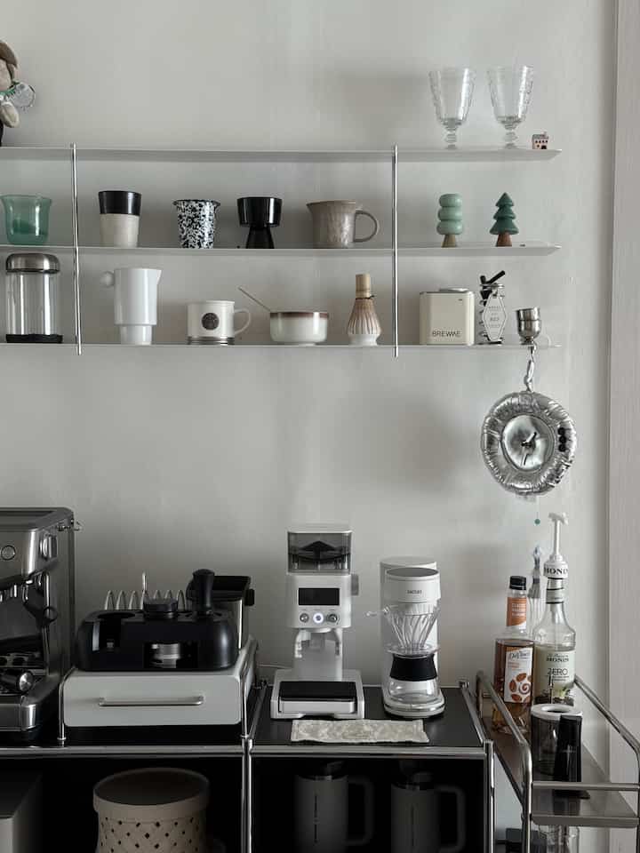 ホワイトの壁に設置された壁棚とコーヒーマシン、収納が配置されたミニマルなホームカフェ空間