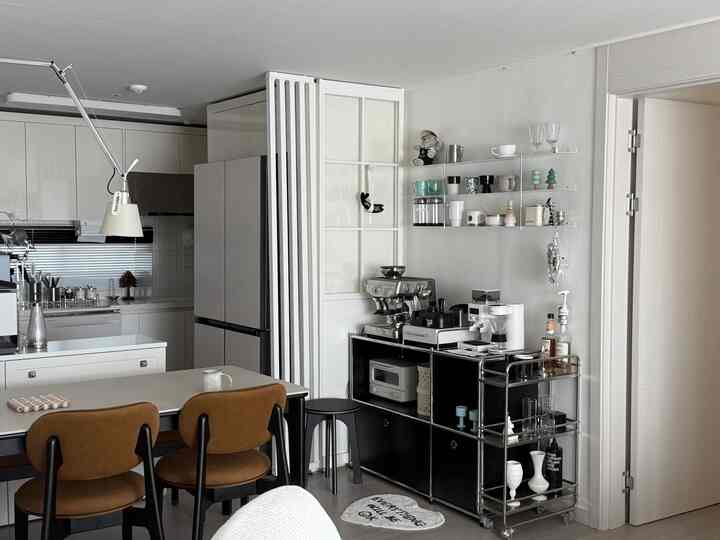 白と茶色のトーンのモダンなキッチンおうちカフェ空間、ダイニングテーブルとコーヒーマシンが配置された清潔感のあるインテリア