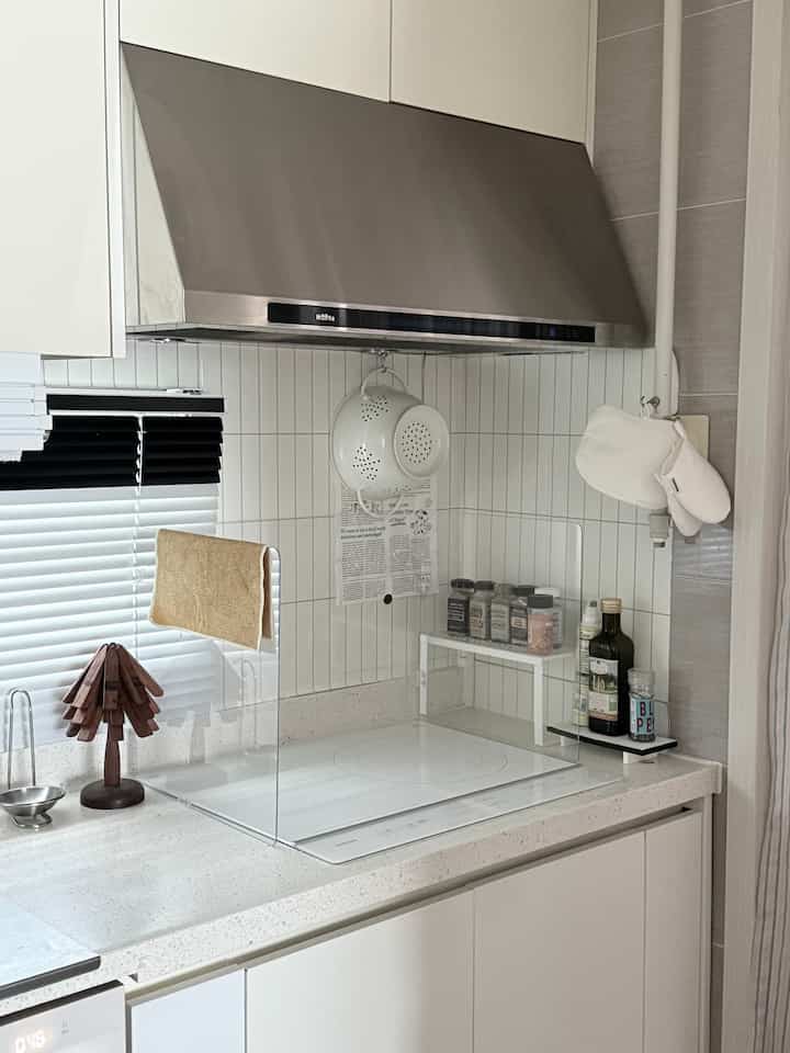 白いタイルとインダクションが配置されたナチュラルな雰囲気の清潔なキッチン