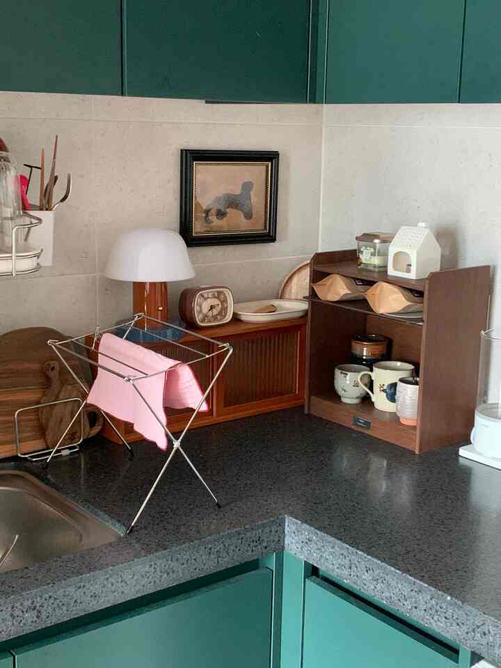 木目調とダークグレーが調和する温かみのあるキッチン、かわいいカップやキャンドルなどのオブジェが雰囲気を演出