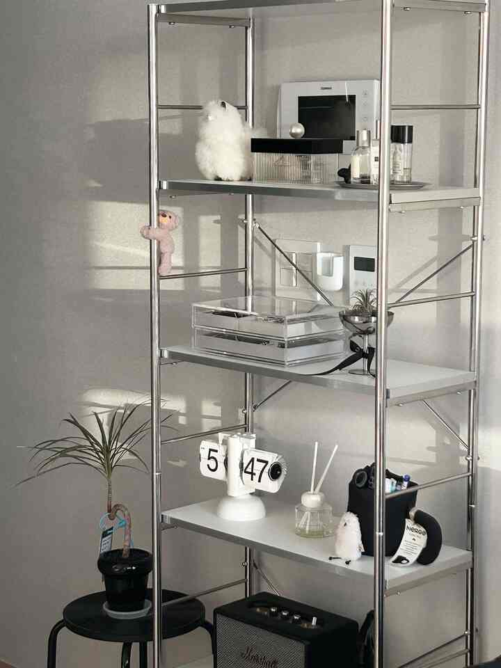 シルバーのメタル棚に透明な収納と複数の装飾品が置かれたナチュラルモダンなインテリア