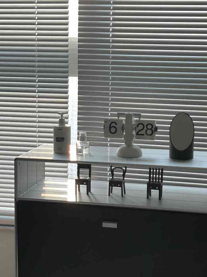 シルバーとブラックのトーンのブラインドを背景にしたモジュール収納キャビネットが配置されたモダンなオフィステルのインテリア