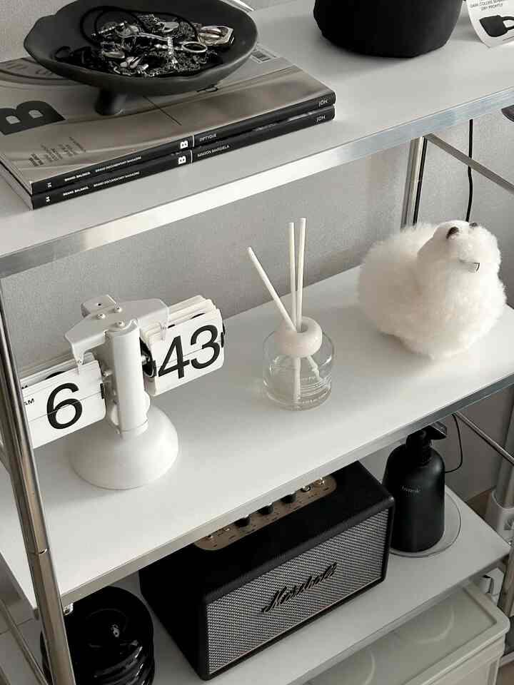 ホワイトトーンの棚空間、時計やディフューザー、ブルートゥーススピーカーが配置されたモダンな印象的なインテリア