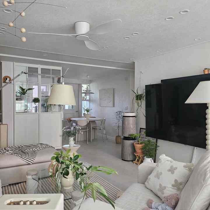 白とナチュラルカラーのリビングルームとキッチン、広いソファと円形ダイニングテーブル、モダンな間仕切りが配置された印象的なインテリア