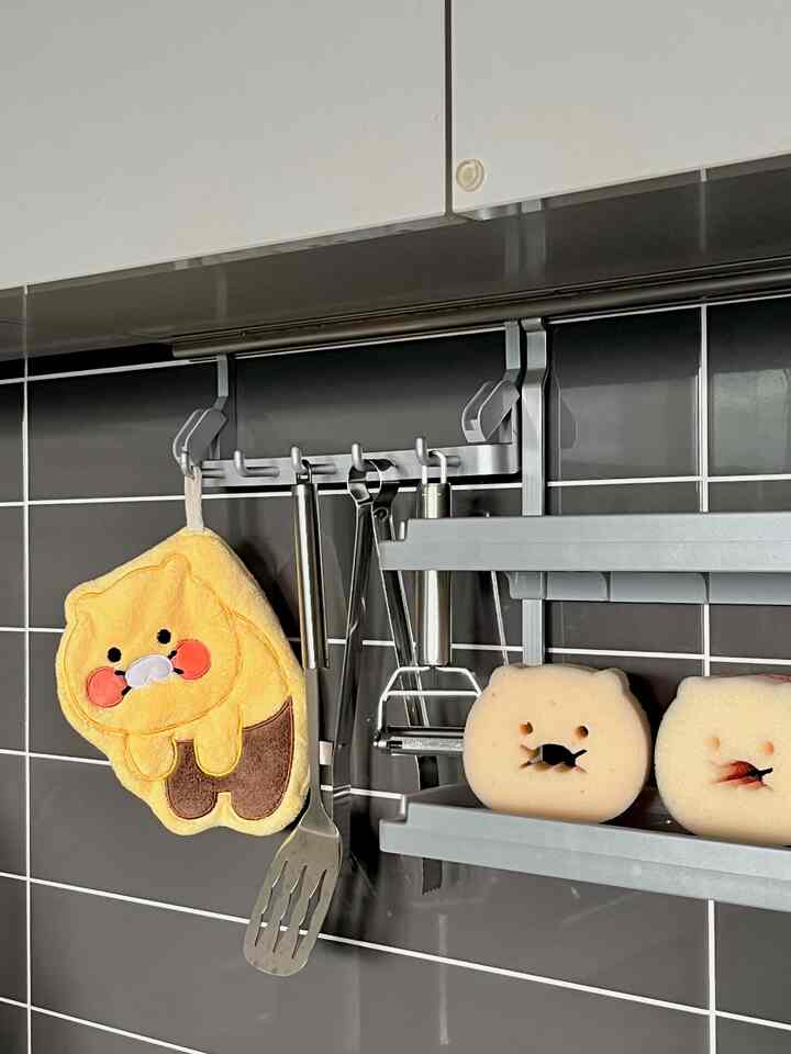 黒いタイルの壁のキッチン空間に、キャラクターハンドタオルと動物型スポンジが配置されたかわいいキッチンアクセサリーの雰囲気