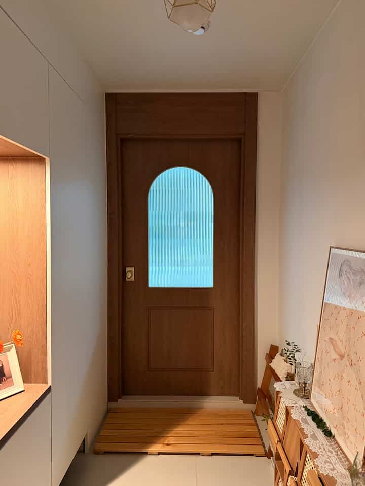 温かみのある木目調の玄関、ウッド中扉とキャビネットが配置された雰囲気あるインテリア