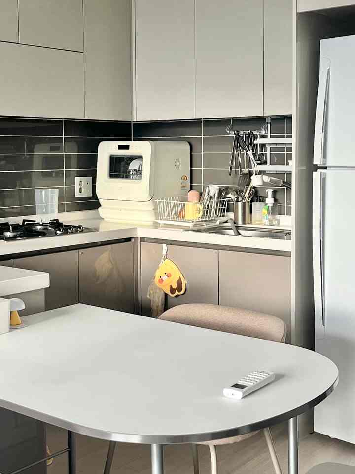 白とベージュのトーンのキッチン、整頓された収納とコンパクトな家具が配置された実用的で清潔感のあるインテリア