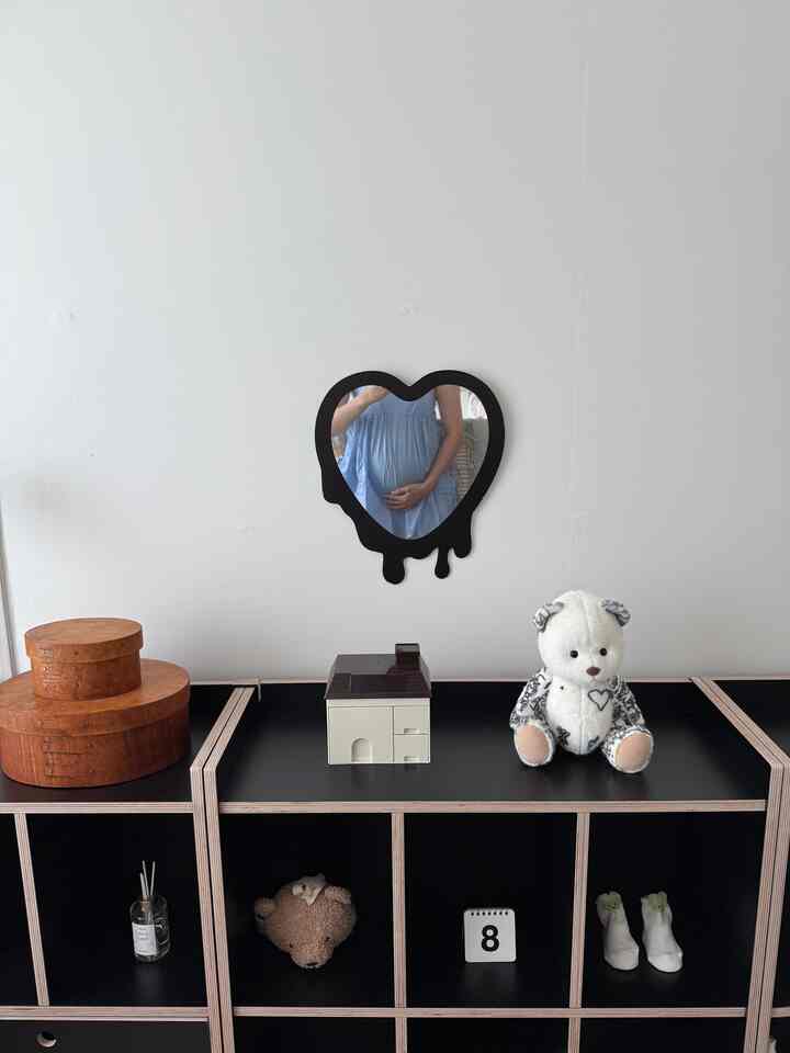 白い壁と黒い収納棚が置かれたウォークインクローゼット、ハート型の鏡と赤ちゃんのぬいぐるみが配された雰囲気のある空間