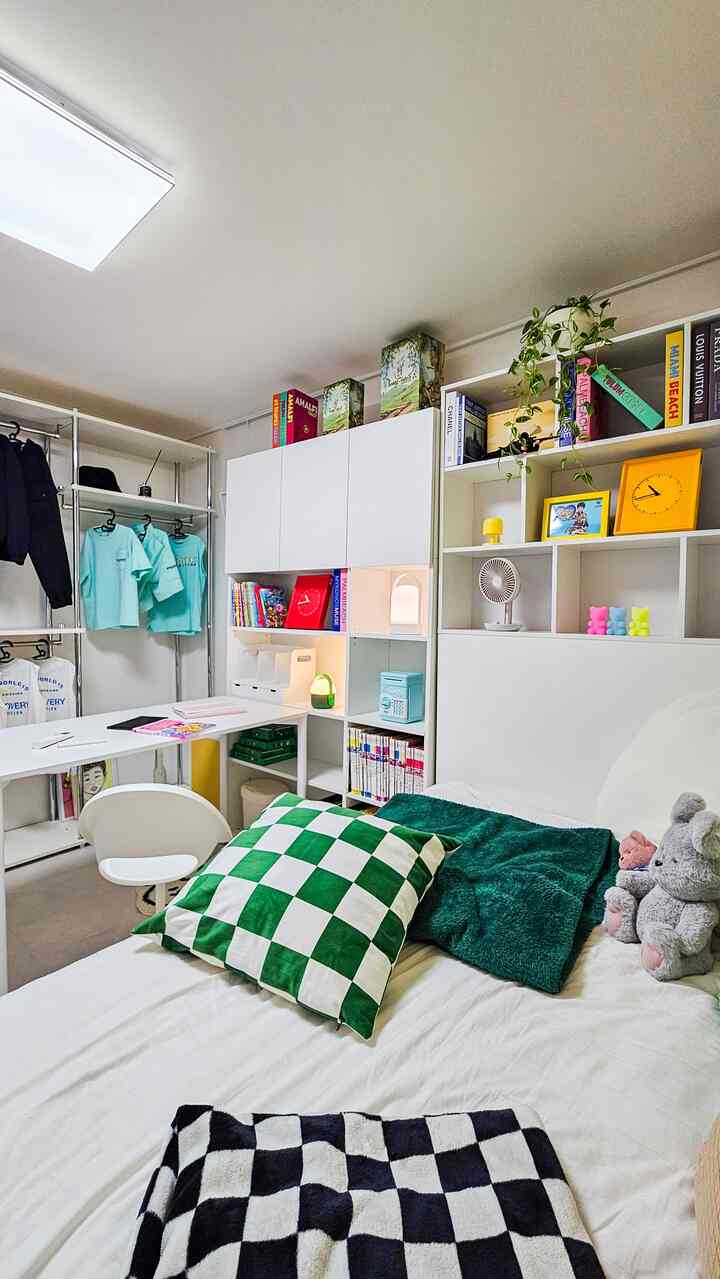 白と緑のトーンが特徴の子供部屋、デスクとベッド、多彩な収納が配置された活気あるインテリア