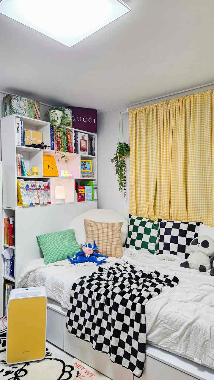 黄色のチェックカーテンと白いベッド、本棚が配された子供部屋で、明るく居心地の良い雰囲気のインテリア