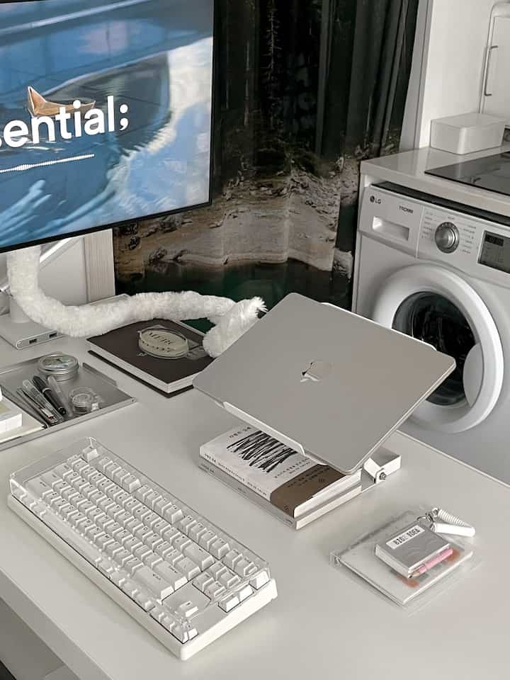 白を基調とした寝室、ノートパソコンスタンドとキーボードが置かれたすっきりとしたホームオフィススペース