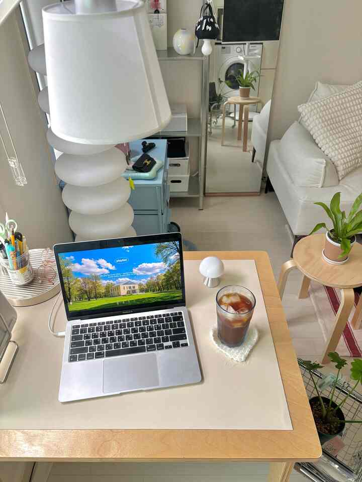 白と木目調が調和したリビング兼おうちカフェ空間、デスクとソファ、スツールが配置された落ち着いた雰囲気のインテリア