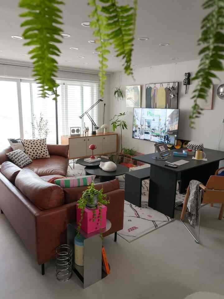 白い壁と茶色のレザーソファ、サイドボードとテーブルランプが配置された雰囲気のあるリビングルーム