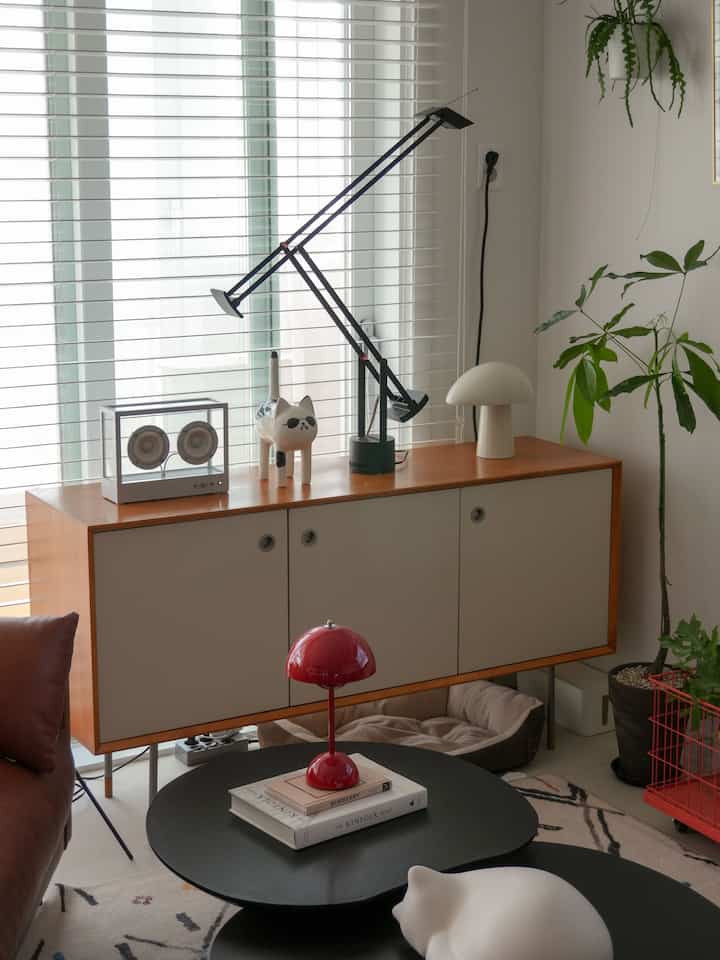 白と木目調が調和したリビング、シンプルなサイドボードの上に照明と猫のオブジェが置かれた自然な雰囲気のあるインテリア