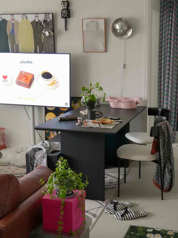 ブラックとホワイトのトーンのダイニングルーム、黒いセラミックのダイニングテーブルと猫のバスケットが配置された雰囲気のあるインテリア