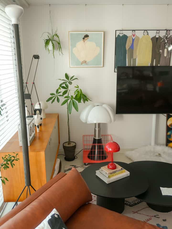 白い壁と木目調の家具が調和するリビング、ブラウンのソファとコーヒーテーブル、壁にポスターが飾られたナチュラルモダンな空間