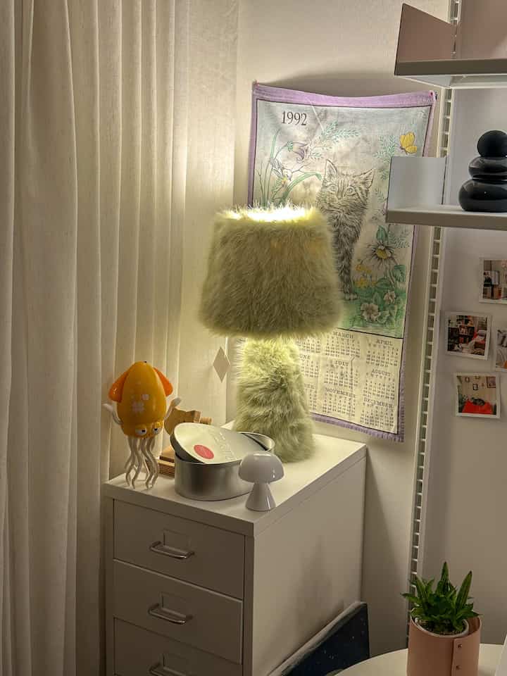 ホワイトとナチュラルトーンの空間、引き出しの上にファーランプと小物が置かれた温かみのあるコーナー