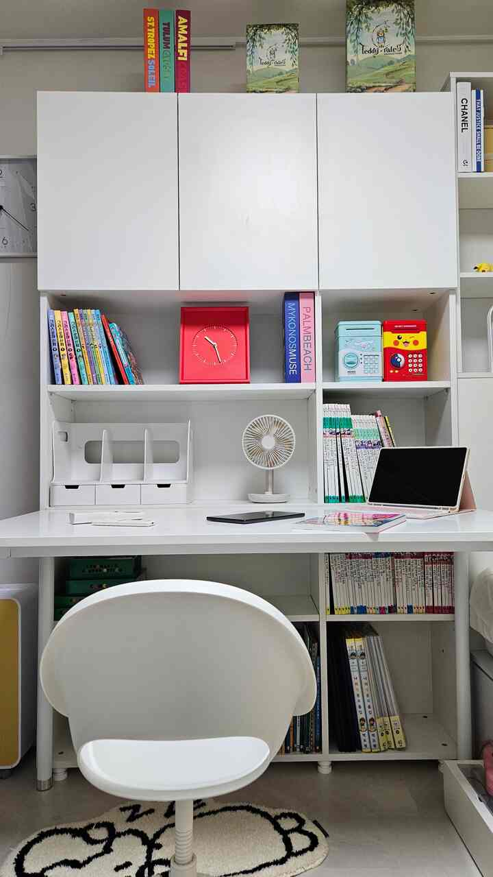 白とモダンな色調の子供部屋、机と本棚に本や小物が整然と配置された印象的な学習スペース
