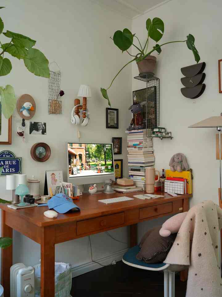 ブラウンの木製デスクと白い壁、緑の植物が配置された雰囲気のあるホームオフィス