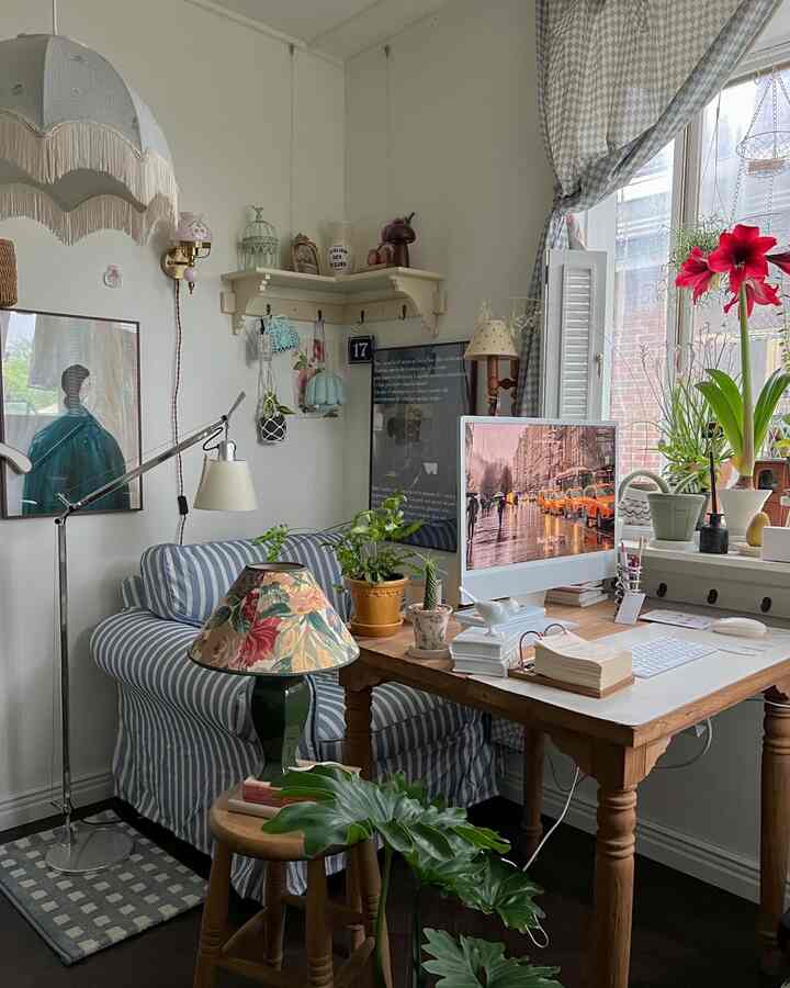 ナチュラルな色調のホームオフィス兼リビング、ストライプのソファと木製のデスク、多様な植物が配置された雰囲気のあるインテリア