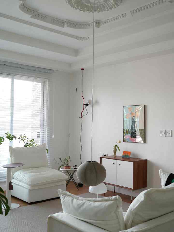 白と木目調が調和したリビングルーム、シンプルなソファとキャビネット、ポスターが配置されたナチュラルモダンなインテリア