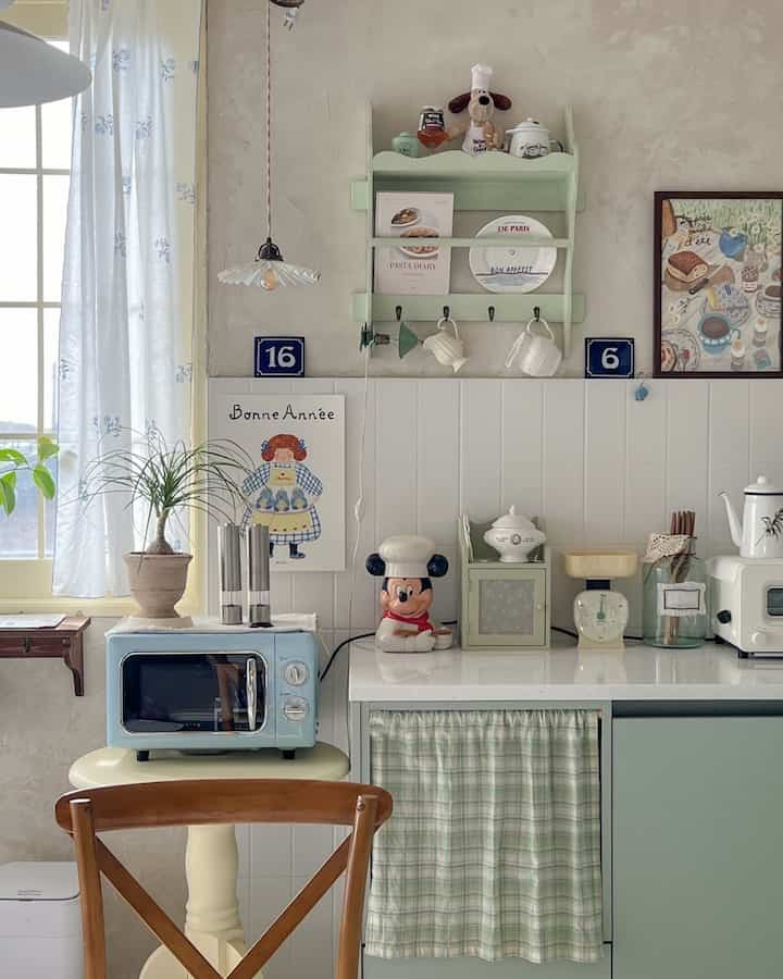 ミント色と白のトーンのキッチン、レトロな電子レンジと飾りが配置された雰囲気のあるおうちカフェ空間