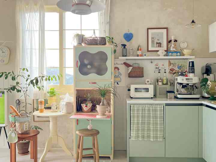 ミント色のL字型キッチンとおうちカフェ空間、自然の植物と木製スツールが調和した雰囲気のあるインテリア