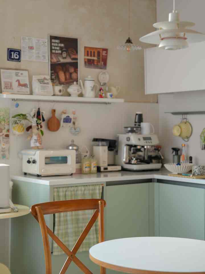 ミント色のコンパクトなキッチン、コーヒーマシンや家電が配置された雰囲気のあるフレンチカントリースタイルのインテリア