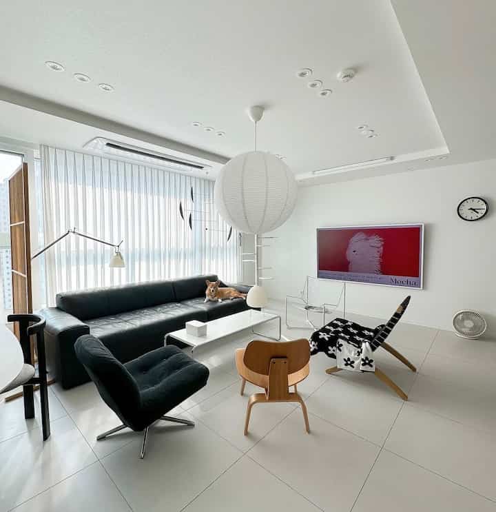 白と黒のトーンのリビング、広々として清潔感のある大きなソファとアームチェアが配置された印象的な空間