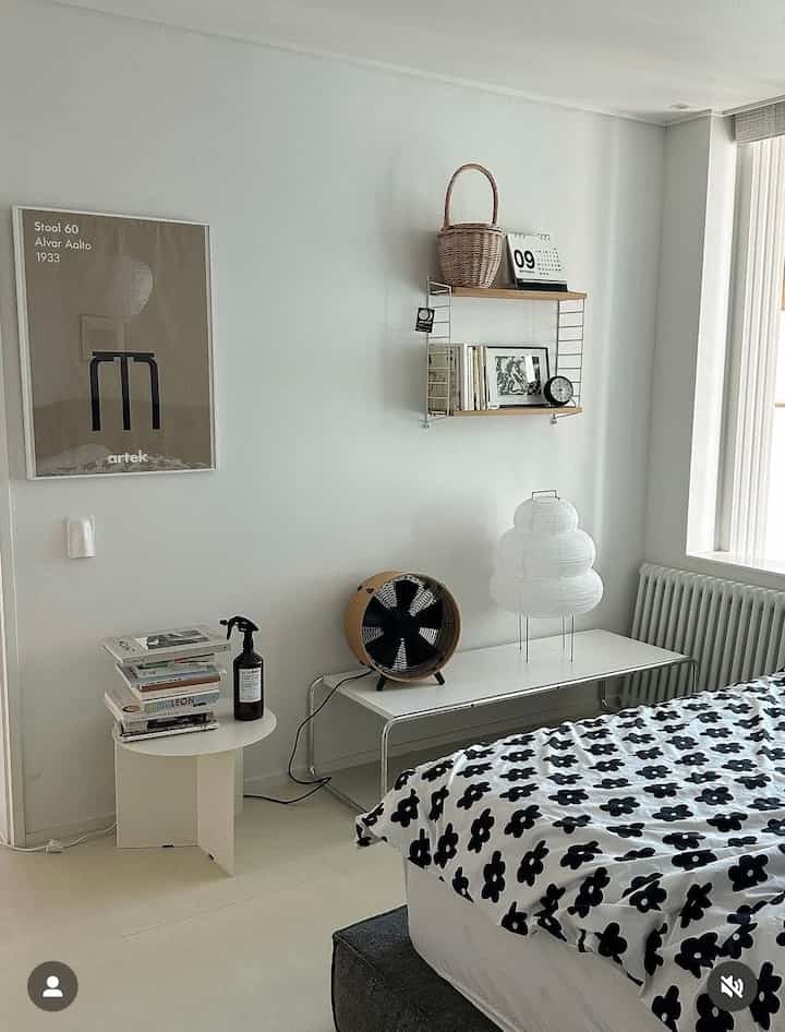 ホワイトとグレーのトーンの子供部屋、ベッドとデスク、壁の棚に時計と本が配置されたモダンな空間