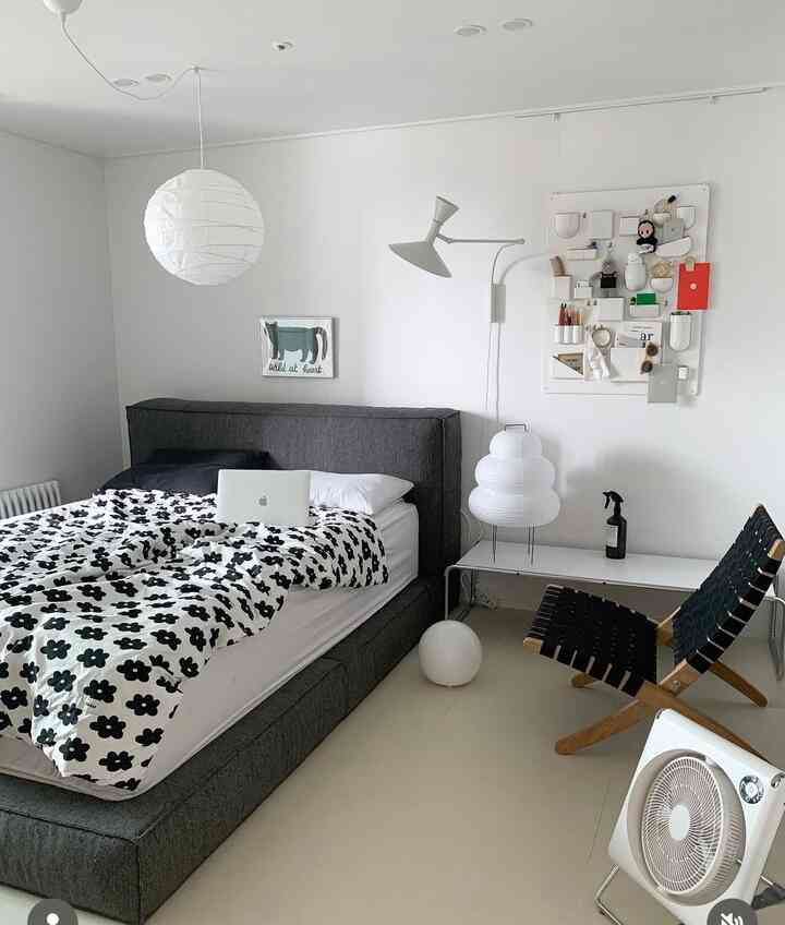 ホワイトとダークグレーのトーンの寝室、大きなベッドとミニマルな家具が配置されたモダンな空間