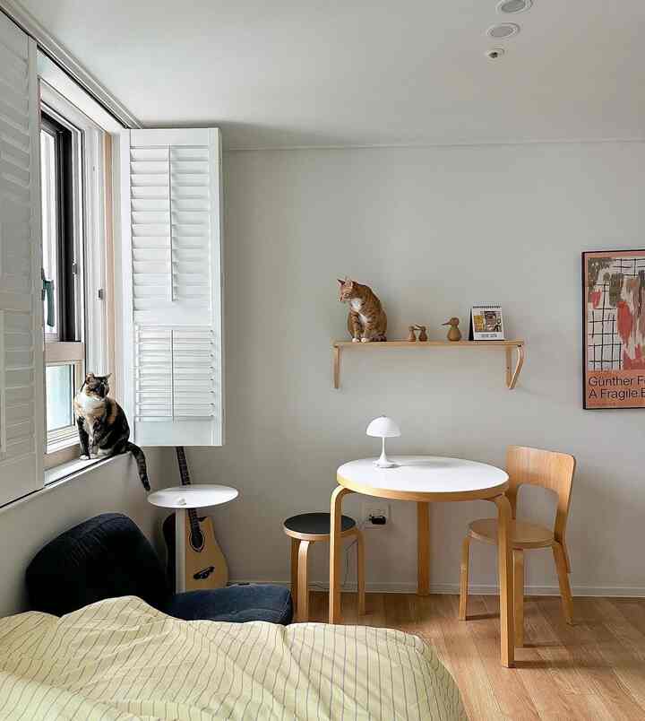 ホワイトと木目調が調和した小さなリビングダイニング、2匹の猫とアルテックのテーブルが配置された落ち着いた雰囲気のインテリア