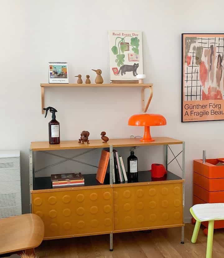 ナチュラルな色調の書斎、木製の棚とオレンジ色のテーブルランプ、整然とした収納が配置された雰囲気のあるインテリア