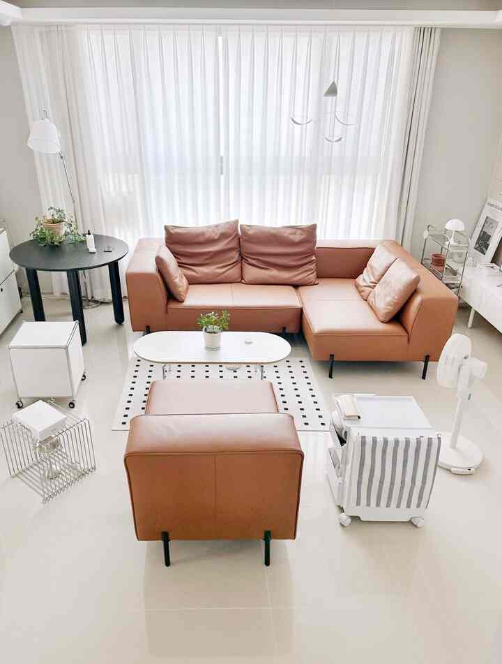 白を基調とした背景にブラウンのレザーソファが配置されたナチュラルモダンなリビングスペース