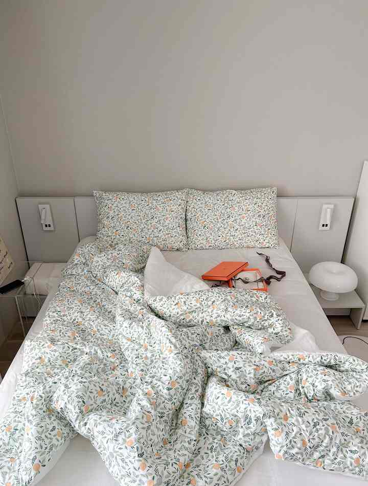 ナチュラルカラーの寝室、花柄のベッドカバーと枕が配置された清潔で居心地の良い空間