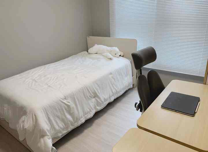 白と木目調の子供部屋、ベッドとデスクが配置された落ち着いた雰囲気のインテリア