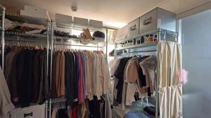 金属製の棚と白を基調とした衣類が配置された狭いワンルームのクローゼットスペース